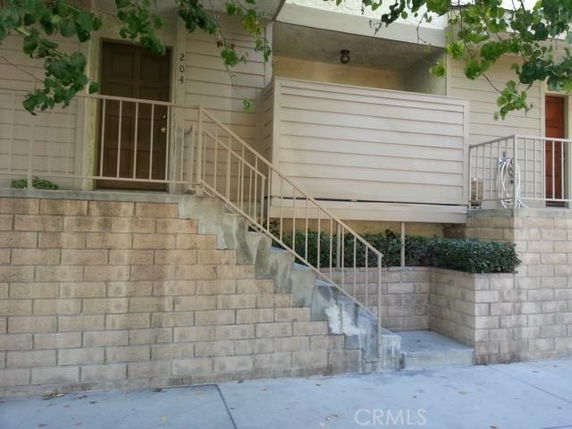 Front view of a small apartment building with stairs and railing.