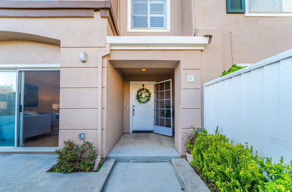 Front view of a house entrance with a decorative wreath on the door and adjacent sliding glass door.