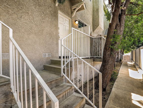 Front view of a multi-story building entrance with steps and railing.