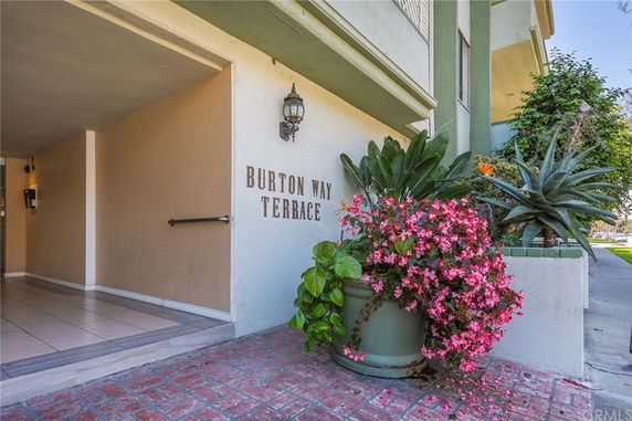Front view of a building entrance with a sign reading 'Burton Way Terrace' and decorative plants.