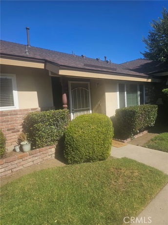 Front view of a single-story house with shrubs and a concrete path.