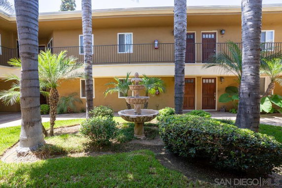 Front view of a two-story building with balconies and a courtyard with a fountain.