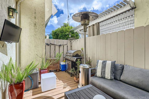 Outdoor patio area with seating, a television, a barbecue grill, and a patio heater.