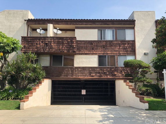 Front view of a multi-story apartment building with a gated entrance.