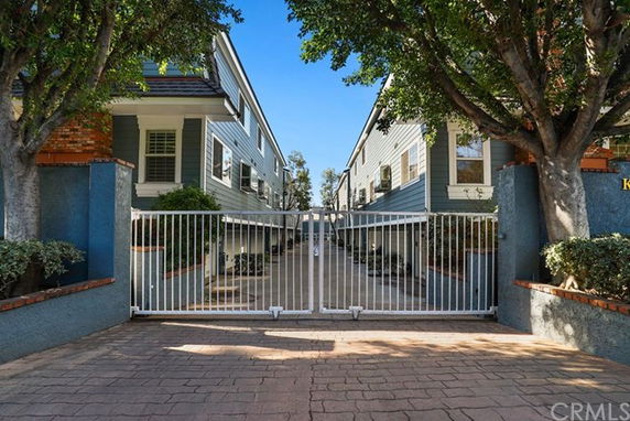 Front view of a gated residential building entrance with two-story structures on either side.
