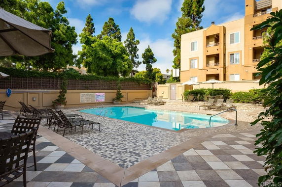 Outdoor swimming pool area with surrounding patio and apartment buildings.