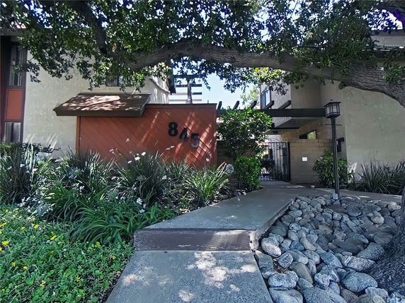 Front view of a building entrance with a wooden panel and a walkway.