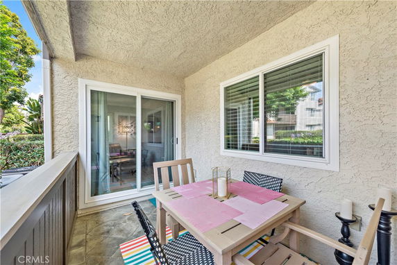 Outdoor patio with a table and chairs next to a sliding glass door.