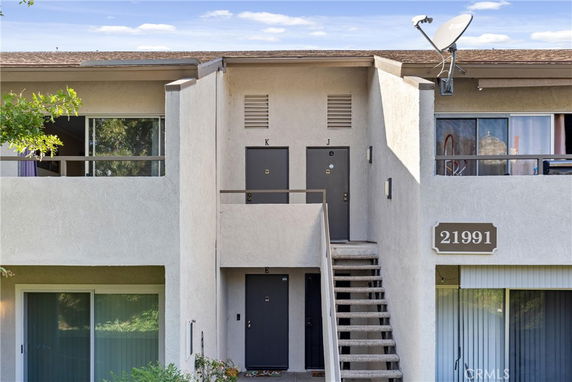 Front view of a two-story residential building with a staircase leading to upper units.