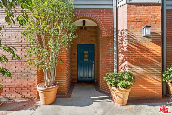 Front view of a brick house with an arched entryway and blue door.