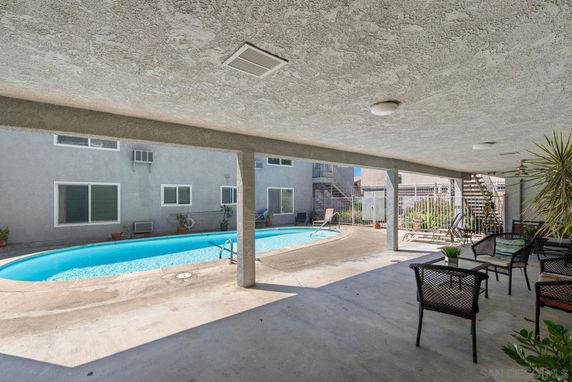 Outdoor area with a swimming pool and seating under a covered patio