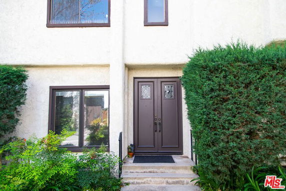 Front view of a house with a double door entrance and surrounding greenery.