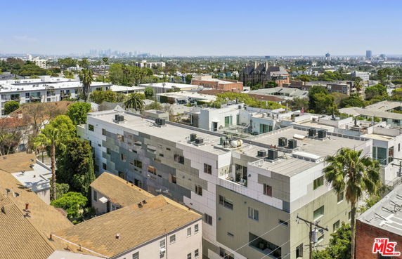 Aerial view of a cityscape with multiple apartment buildings, showcasing rooftops with HVAC units and a distant skyline.