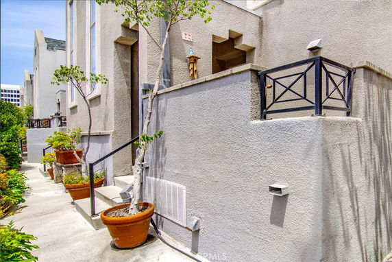 Exterior view of a multi-story building with a walkway and potted plants.