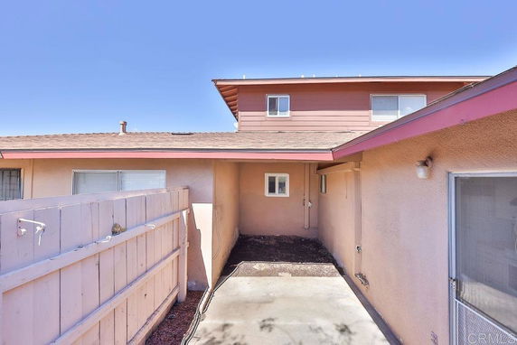 Back view of a two-story house with beige walls and a patio area.
