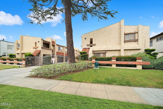 Front view of a multi-story residential building with beige facade and gated entrance.