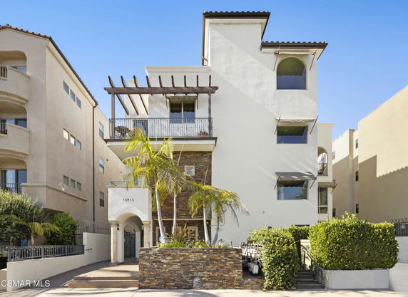 Front view of a multi-story building with a balcony and arch entrance.