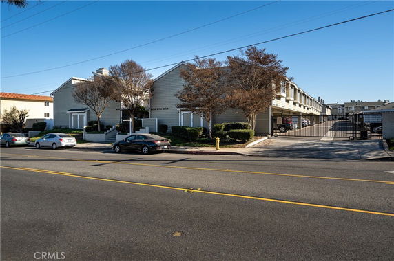 Front view of a residential building with multiple units and a gated parking area.