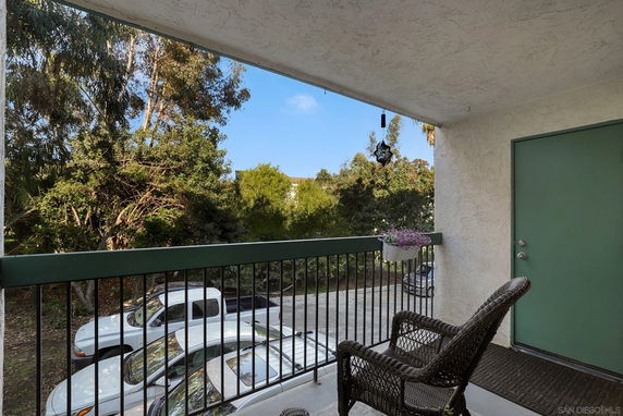 Balcony overlooking parking area with trees and parked cars visible.