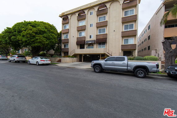 Front view of a multi-story residential building with parking space in front.