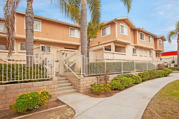 Front view of a two-story apartment building with a staircase and railing.