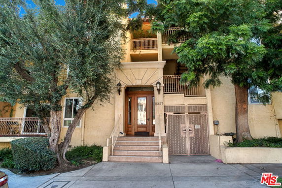 Front view of a multi-story building with a wooden entrance and metal railing balconies.