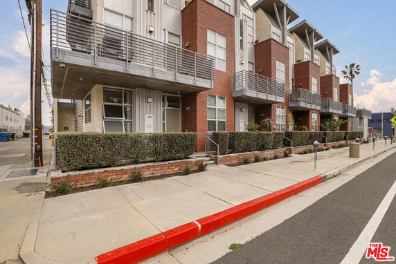 Front view of a modern multi-story building with balconies and red brick facade.