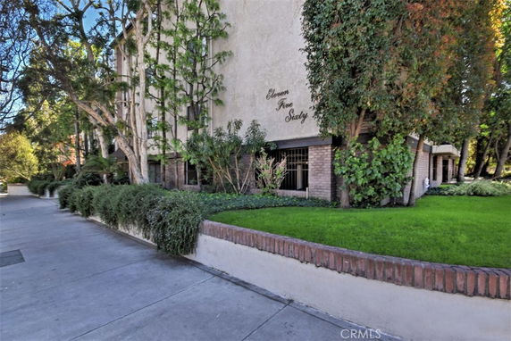 Front view of a building with brick and stucco exterior, surrounded by greenery.