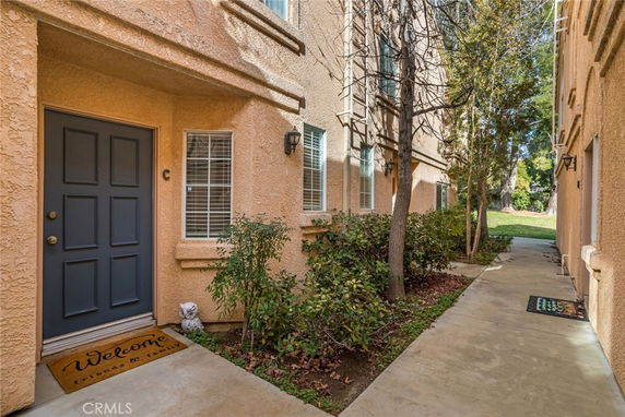 Front view of an apartment building with a blue door and welcome doormat.