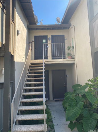 Front view of a multi-story building with external staircase and two upper-level doors.