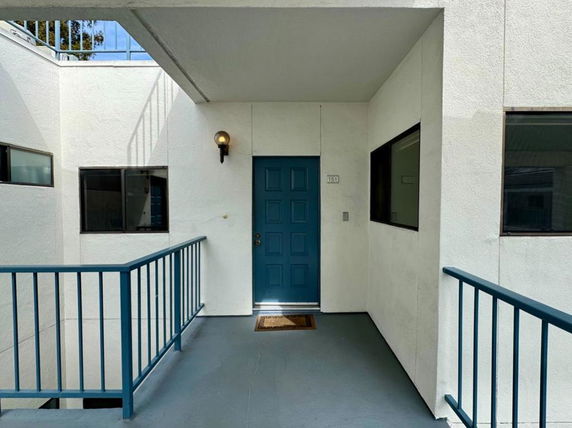 Front entrance of a building with a blue door and railing.