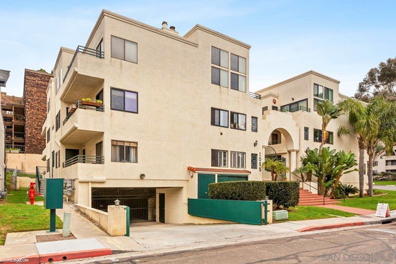 Front view of a multi-story apartment building with balconies and entrance archway.