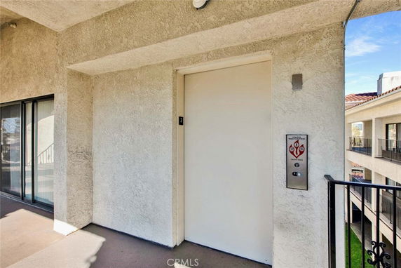 View of a building exterior with an elevator door on an outdoor walkway.