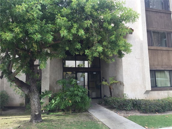 Front view of a building with a glass entrance and surrounding greenery.