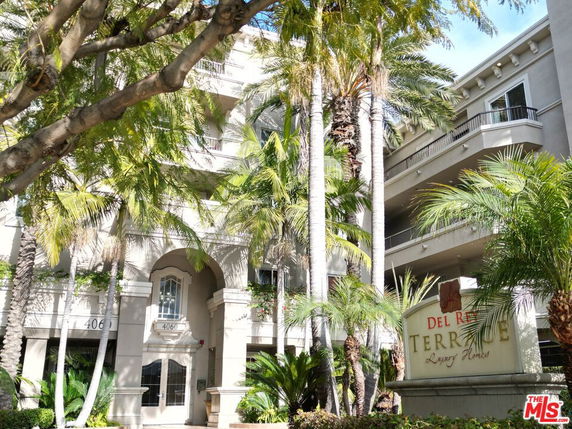 Front view of a luxury apartment building with balconies and palm trees.