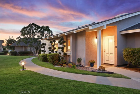Front view of a single-story house with a walkway and exterior lighting.