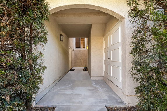 Front entrance view of a house with an arched walkway and side door.
