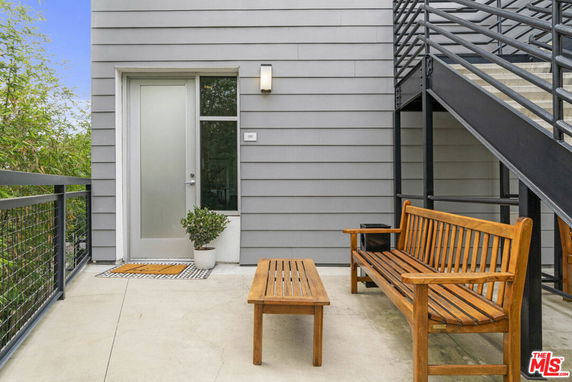 Entryway of a building with a metal door, railing, and outdoor seating.
