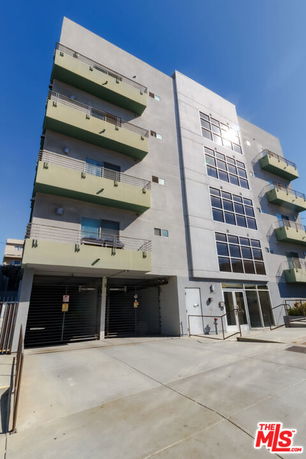 Front view of a multi-story apartment building with balconies and large windows.