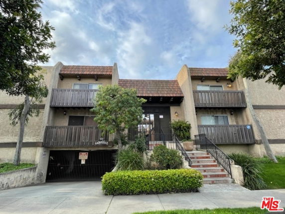 Front view of a multi-story residential building with balconies and a central entrance.