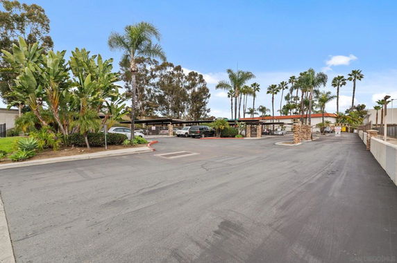 Open outdoor parking area with covered parking spaces and tropical landscaping.