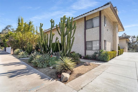 Front view of a two-story house with a sloped roof and surrounding cactus plants.