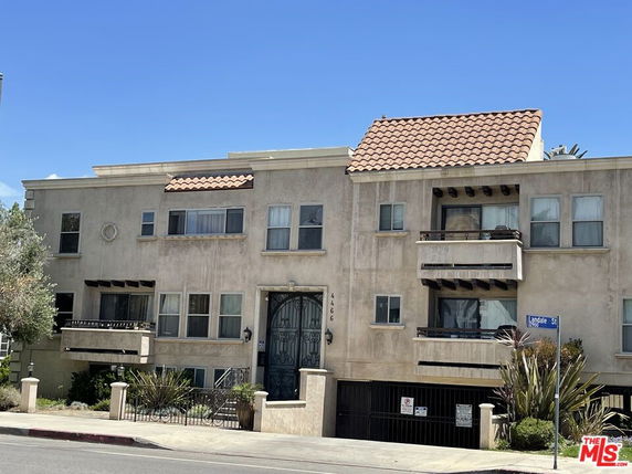 Front view of a multi-story residential building with balconies and gated entrance.