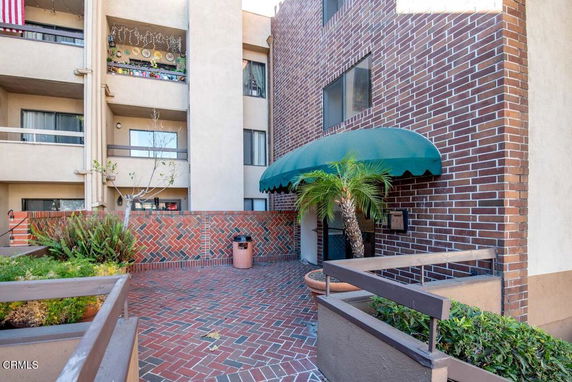 Front view of a multi-story brick building with balconies and a green awning over the entrance.