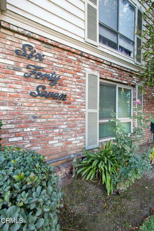 Front view of a brick house with horizontal siding on the upper level and window shutters.