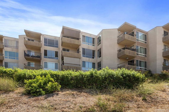 Front view of a multi-story apartment building with balconies and large windows.