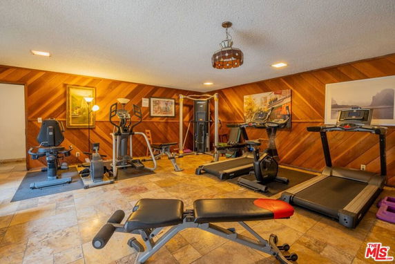 Indoor gym area with various exercise equipment and wood-paneled walls.