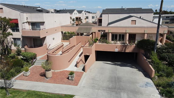 Front view of a multi-story residential building with a garage and a landscaped entrance.