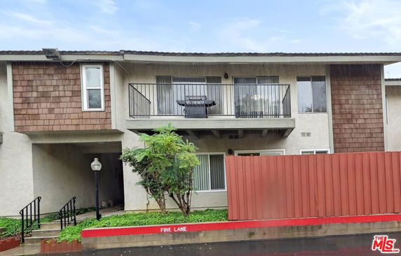 Front view of a two-story residential building with a balcony on the upper floor.