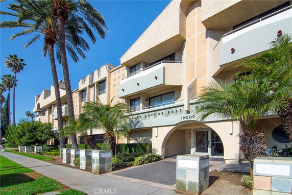 Front view of a multi-story building with balconies and palm trees.